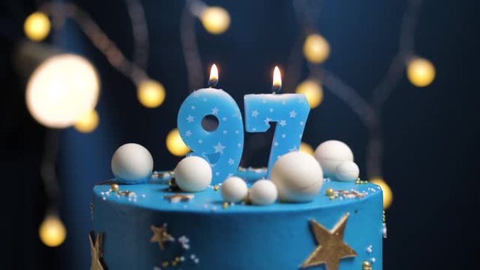 生日蛋糕编号97星星天空和月亮概念，蓝色蜡烛被打火机点燃，然后吹灭。如果需要，请在屏幕右侧复制空间。