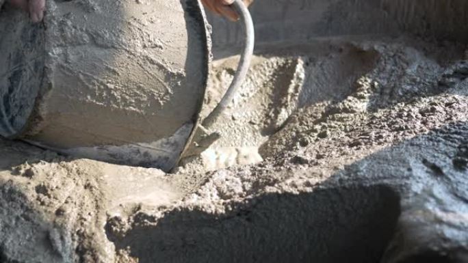 建筑工人或泥水匠在施工现场将混合的混凝土挖入桶中。施工概念。
