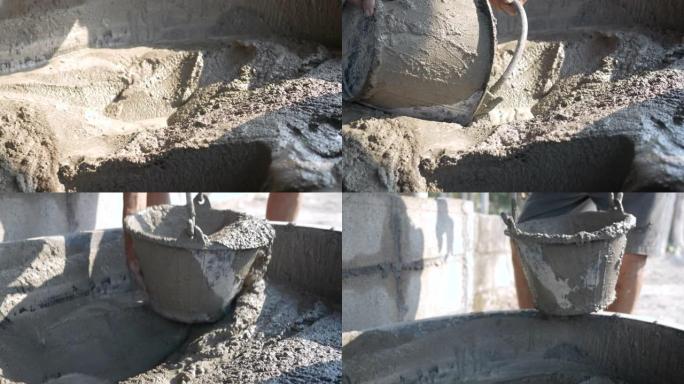 建筑工人或泥水匠在施工现场将混合的混凝土挖入桶中。施工概念。