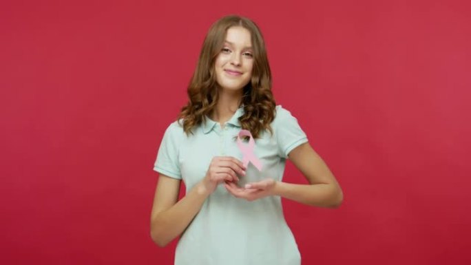 可爱的年轻女子穿着马球t恤，手持粉色丝带，乳腺癌意识的象征，女性保健