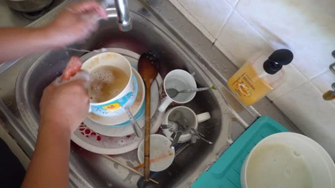 男人手工做家事洗碗在水槽里用手冲洗盘子