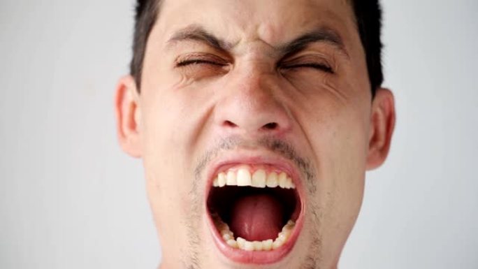 年轻的高加索愤怒的家伙的肖像直接对着镜头大喊。男人在白色背景上的情感。特写。