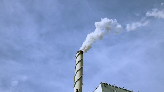 蓝天背景下烟囱冒出的白烟视图。生态学和温室效应概念。