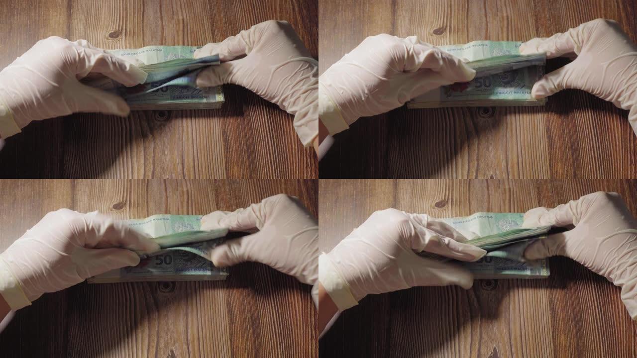 女性手用医用手手套计算马来西亚钞票。财务概念，会计概念。
