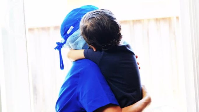 小男孩拥抱他的母亲，他是一名医护人员，他已经好几个星期没见了，因为她正忙着治病，因为新型冠状病毒肺炎