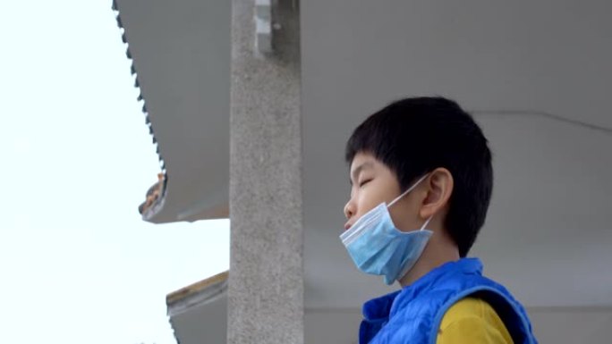 亚洲男孩戴着防毒面具，在户外吃饭