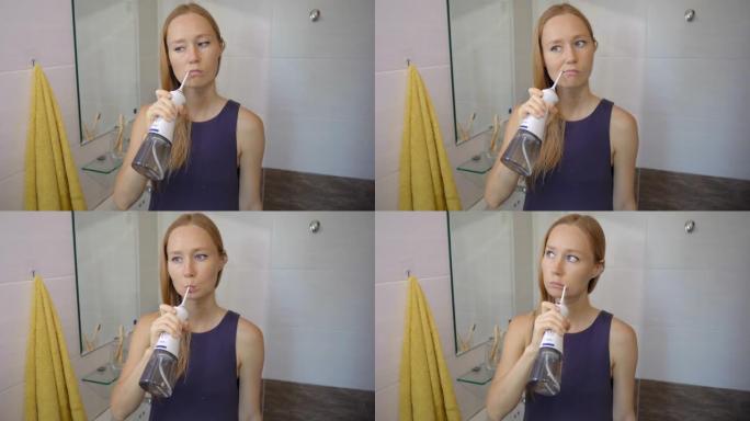 一名年轻女子使用便携式牙线器牙科口腔冲洗器清洁牙齿。牙齿护理概念
