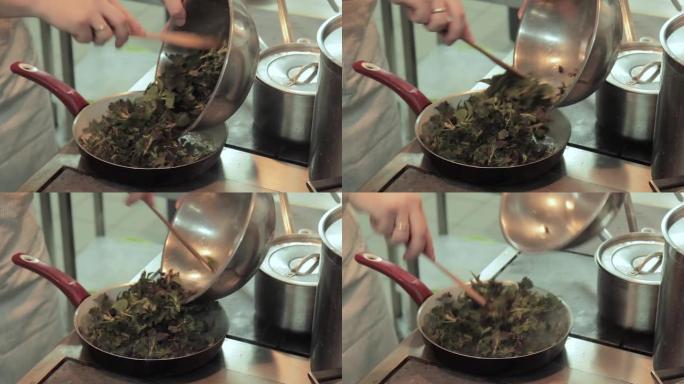 厨师将荨麻的叶子放入餐厅厨房的锅中。厨师在锅上搅拌和炸薯条野荨麻作为鱼粉