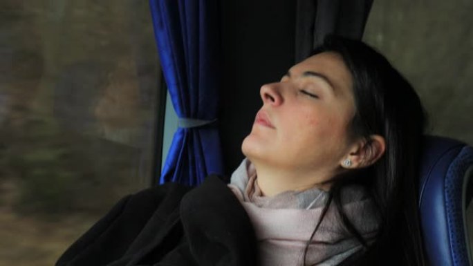 坦率的现实生活中的女乘客在公路上旅行时在公共汽车上睡着了。睡在公共汽车窗户旁边的正宗女孩