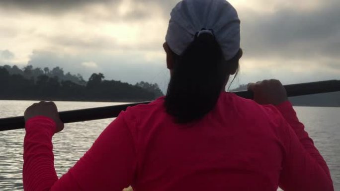 亚洲妇女早晨在热带大湖皮划艇。放松运动