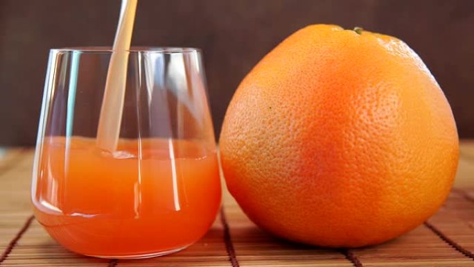 葡萄柚汁倒入玻璃杯和新鲜的葡萄柚。柑橘维生素汁在一个透明的玻璃水果。