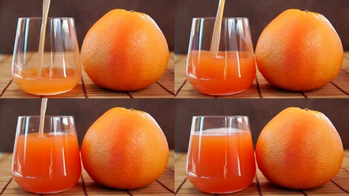 葡萄柚汁倒入玻璃杯和新鲜的葡萄柚。柑橘维生素汁在一个透明的玻璃水果。