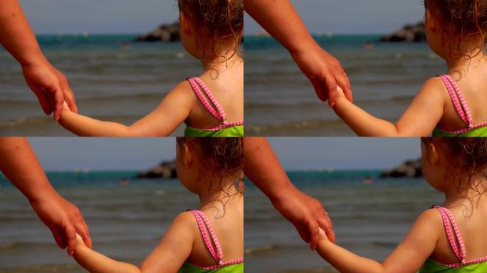 母亲的手在大海的背景上牵着女儿的手