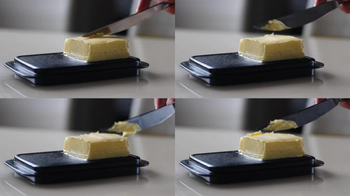 一个男人用刀在桌子上拿黄油做三明治