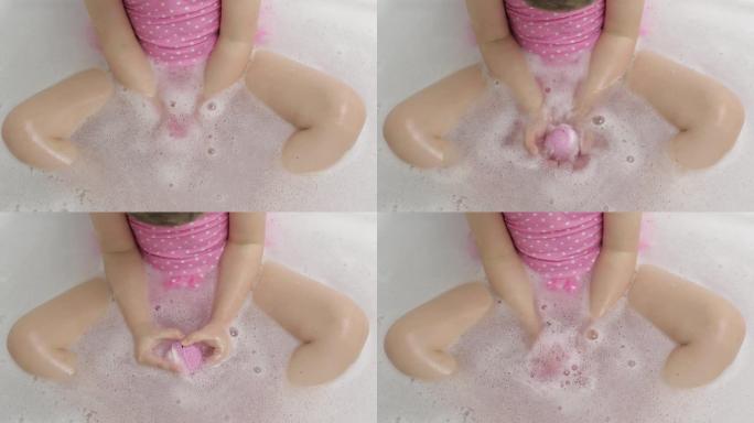 女孩的手把洗澡炸弹放在水里。浴盐球溶解在水中