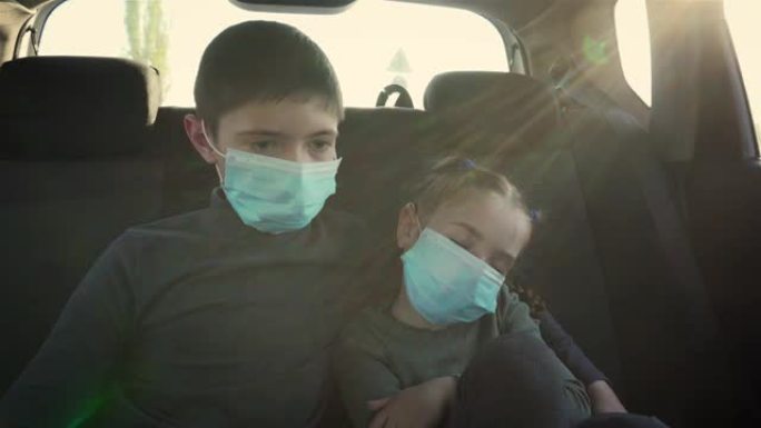 戴着医用面具的电影镜头女孩睡在她哥哥旁边的移动汽车后座上。儿童面部的保护手段，以防止阳光照射下的冠状