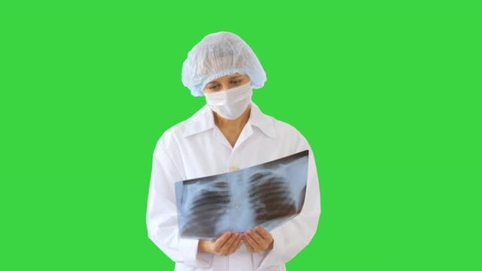 戴着医用口罩的女医生在绿色屏幕上看x射线图像，色度键