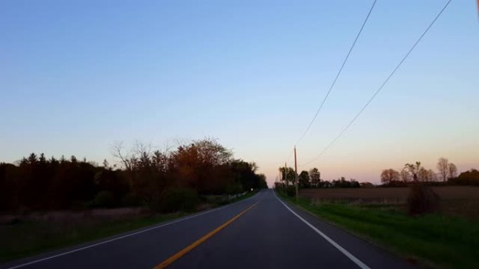 * 反向运动 * 在日落后退时间流逝期间驾驶乡村道路。黄昏傍晚时分，太阳在地平线上升起时，司机的观点