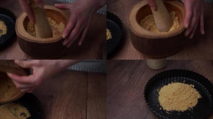 用带有杵的木制研钵中的饼干制成的细碎粉末状dame倒在专业的不粘蛋糕盘中。