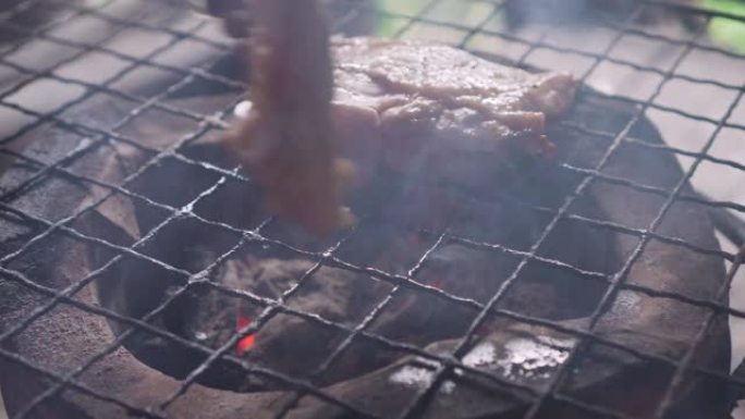 鸡大腿在传统的炉子上烤制。充满了炽热的火焰和烟雾。具有户外感觉的泰国街头美食。