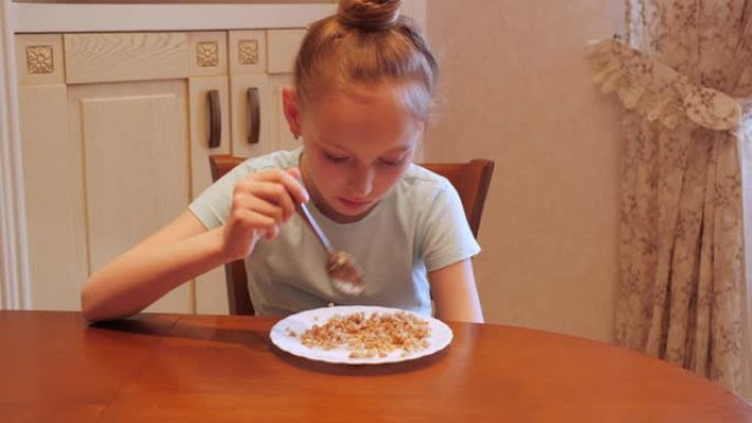 十几岁的女孩在家庭厨房吃荞麦粥。年轻女孩在厨房餐桌上吃荞麦。饮食营养和健康食品。