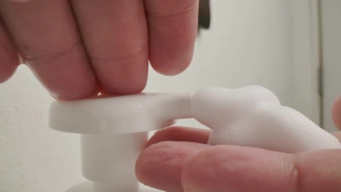 一名男子的手使用消毒剂肥皂泡沫清洁手卫生预防电晕病毒爆发。男人使用一瓶抗菌消毒剂肥皂。
