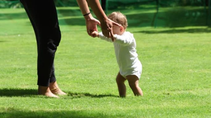 可爱的宝宝在草坪上学习走路。婴儿幼儿在户外的第一步