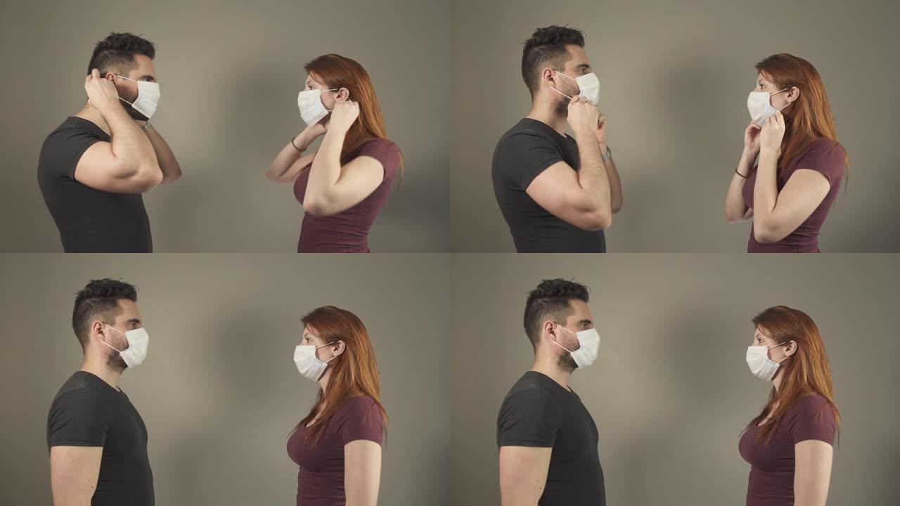在法国新型冠状病毒肺炎大流行病毒期间，戴着外科口罩的孤立夫妇站在工作室里面对。4K UHD。两个年轻