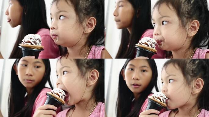 亚洲孩子在家和姐姐一起吃冰淇淋蛋卷，慢动作。