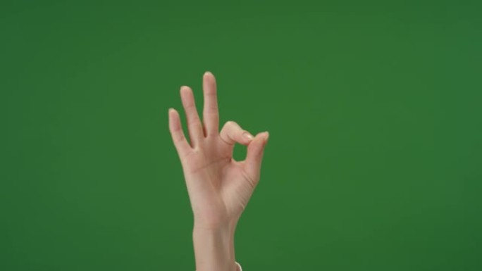 女性手在绿色屏幕上做出OK手势