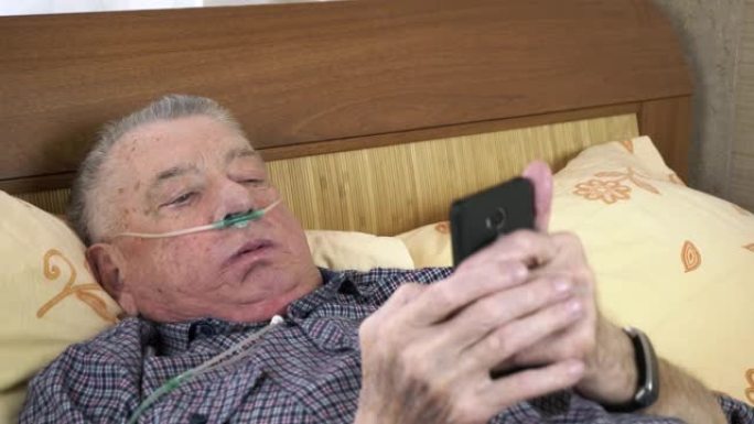 老人躺在床上，看着装有医用氧气导管的智能手机