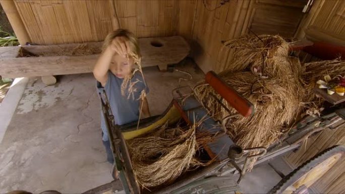 一个小男孩玩古老的大米处理工具的慢动作镜头