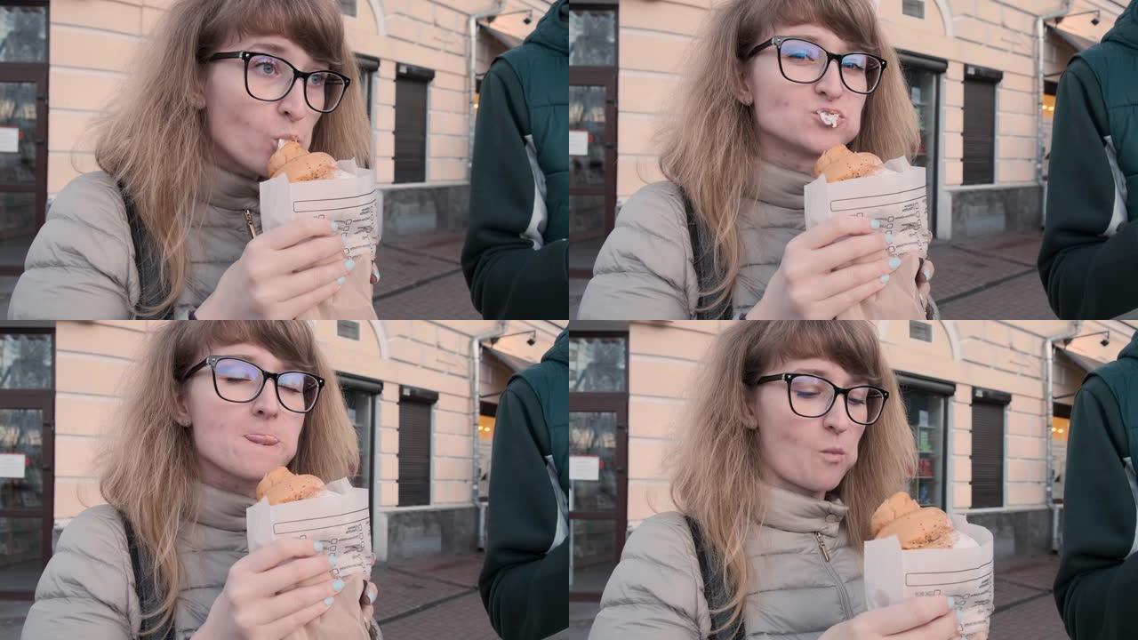 有趣的年轻女孩吃羊角面包，站在街上看着相机
