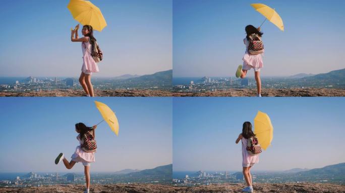 女孩背着背包，拿着黄色的伞在城市景观的顶部跳舞，生活方式的概念。