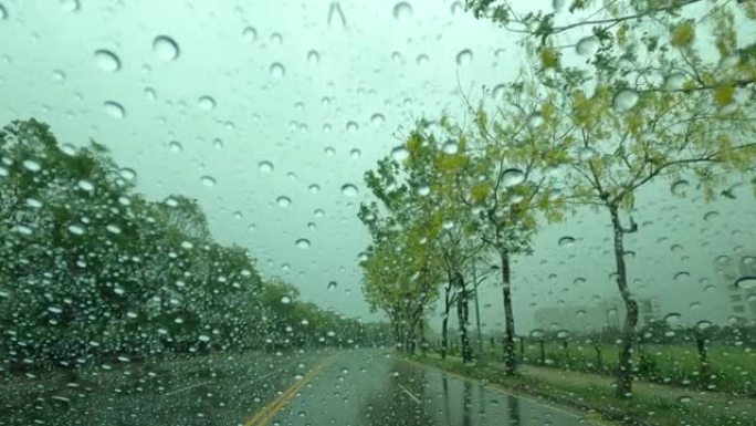 通过带有雨滴的车窗观看道路，在雨中行驶