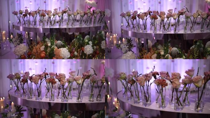 婚礼装饰。在光子区的背景上燃烧蜡烛。花瓶里的玫瑰摆在新婚夫妇的桌子上。蜡烛在模糊的背景上燃烧。