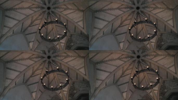 从底部观看旧吊灯的形式，轮子上的灯泡挂在教堂或另一栋旧建筑的天花板上。行动。漂亮的复古风格
