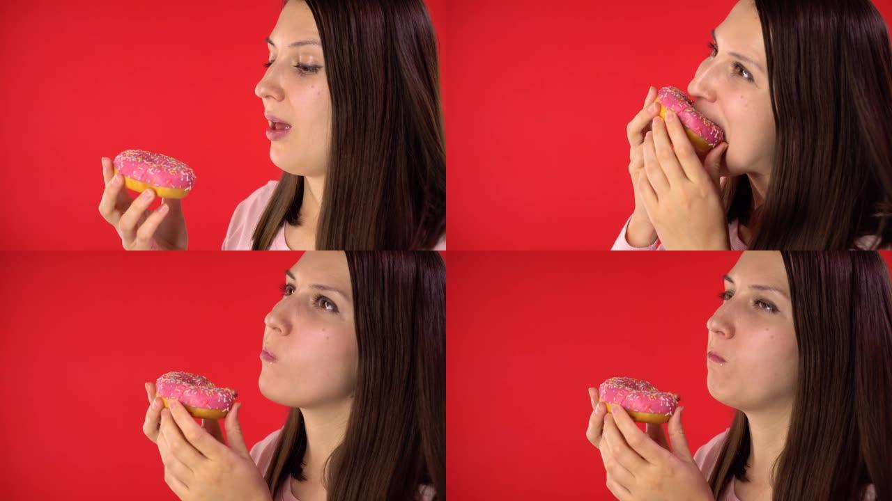 一个黑发女孩的特写镜头。女孩手里拿着一个釉面甜甜圈，然后慢慢地咬着，愉快地咀嚼着