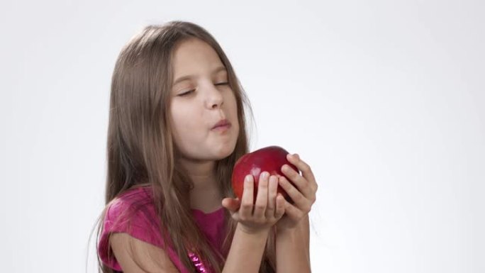 白色小女孩吃一个大红苹果。一个女孩咬了一块红灰，尝了尝。