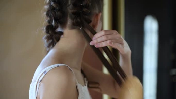 年轻女子在走廊的镜子前编织辫子