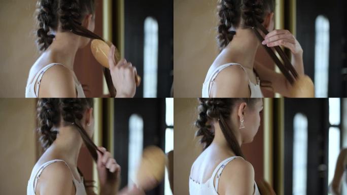 年轻女子在走廊的镜子前编织辫子
