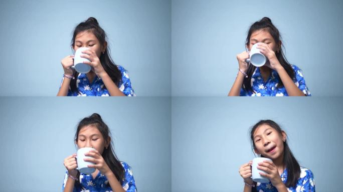 亚洲女孩喝蓝色杯子和蓝色背景。