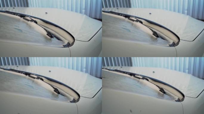 封闭的汽车在挡风玻璃上覆盖着白色的洗涤活性泡沫。车辆清洁服务