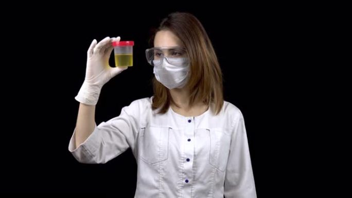 一位年轻的女医生正在检查尿液检查。一名妇女在黑色背景上检查装有尿液的测试罐。