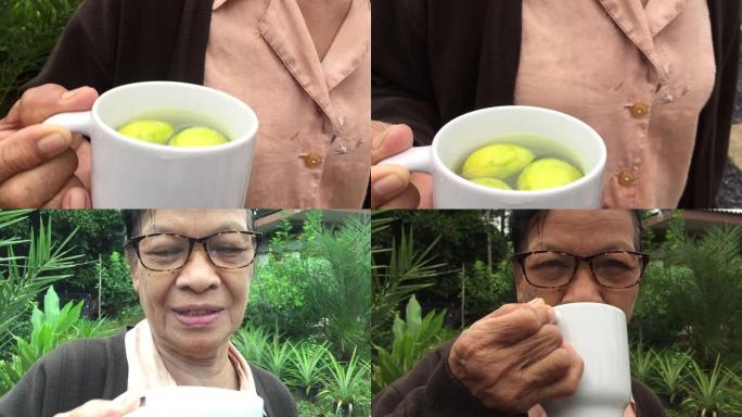 亚洲泰国老妇喝健康饮料热水与新鲜有机酸橙切片