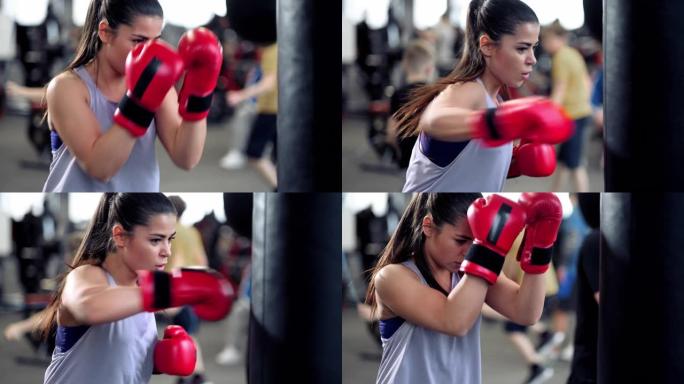 运动年轻的黑发女人在运动服装和红色拳击手套训练撞在一个拳击袋在健身馆。