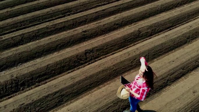 航空。女农民、农学家以特殊的土壤行在田间。她用药片测试拖拉机自动种植土豆的质量。现代农业,农业。春天