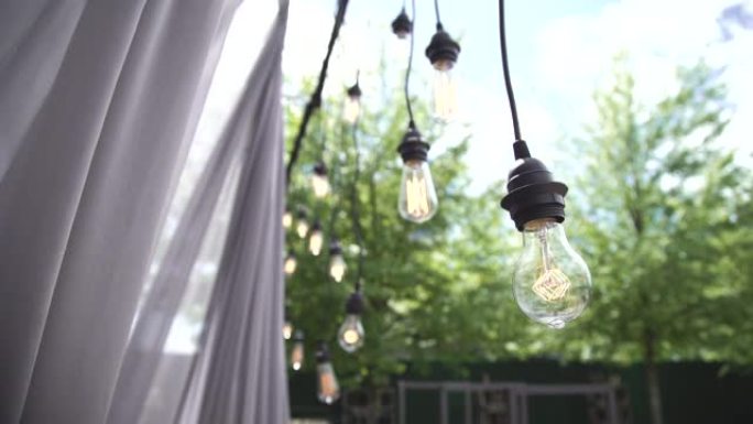 慢动作灯泡剪辑爱迪生有线复古风格悬挂在活动期间自然电影拍摄慢动作聚焦和失焦时尚婚礼仪式户外活动