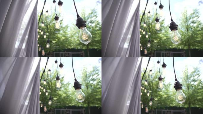 慢动作灯泡剪辑爱迪生有线复古风格悬挂在活动期间自然电影拍摄慢动作聚焦和失焦时尚婚礼仪式户外活动