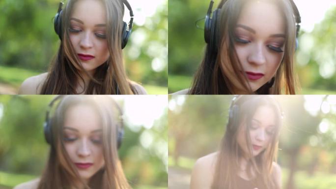 在公园大自然外面戴着耳机听音乐的漂亮女孩。梦幻的年轻20岁女子听歌